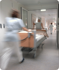 Staff rushing a patient trolley down a hospital ward
