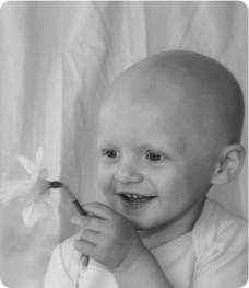 A young baby boy with no hair holding a daffodil