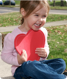 Happy young girl clasping a big foam heart to her chest