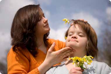 Down syndrome child having flowers placed in her hair by her mother