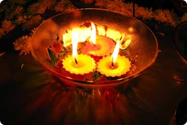 3 tea candles burning in a golden bowl