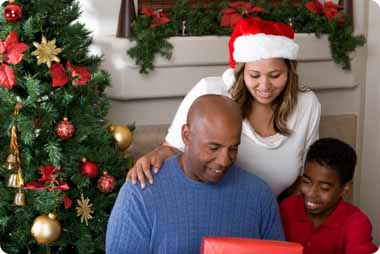 A young family opening presents infront of a Christmas tree